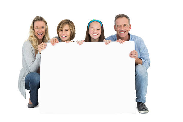 istock Cute family smiling at camera holding poster 518355341