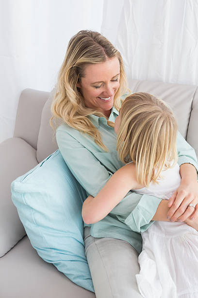 istock Mother sitting on couch with daughter smiling at camera 518355751