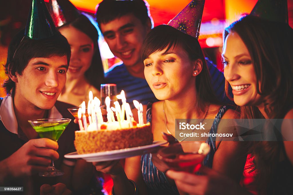 Blowing on candles in the dark Charming female blowing on candles on birthday cake after making her wish at party Birthday Stock Photo