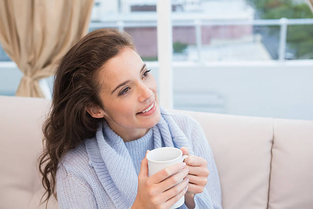 istock Pretty brunette having coffee on the couch 518357115