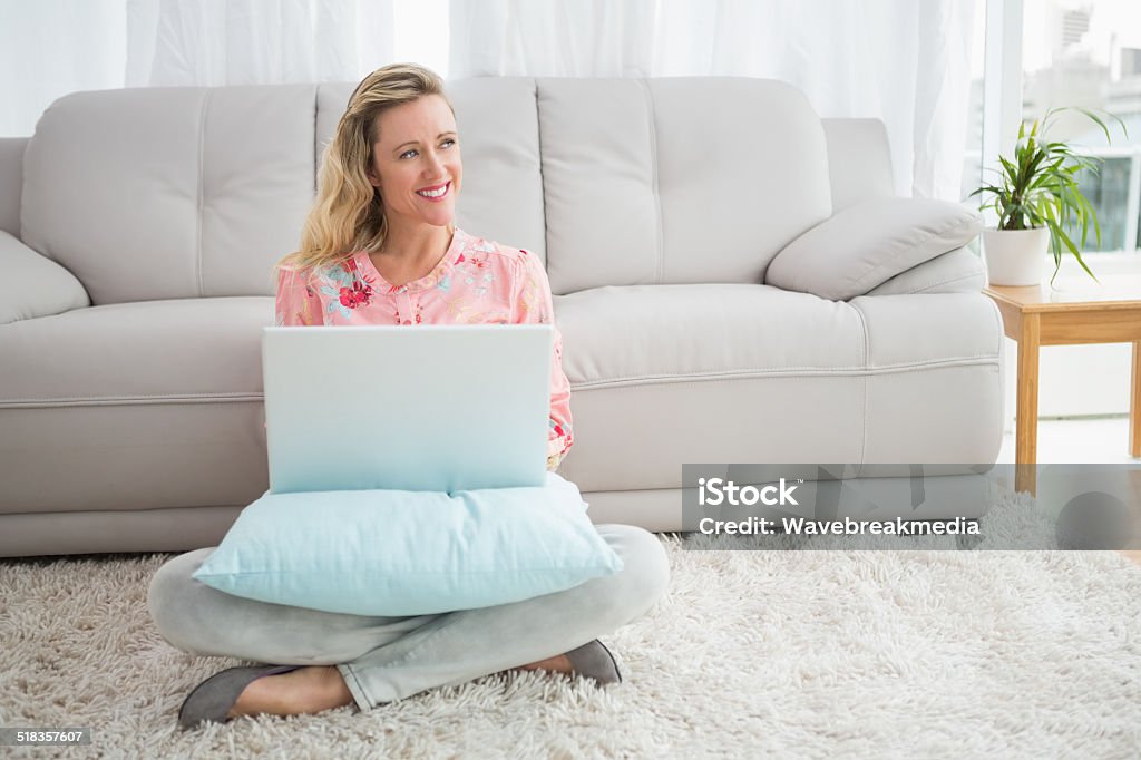 Beautiful blonde woman sitting on the floor using laptop Beautiful blonde woman sitting on the floor using laptop  at home in the living room 30-39 Years Stock Photo