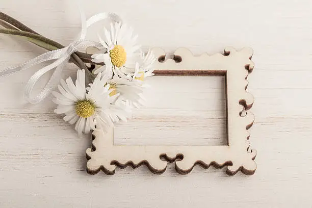 daisy flowers and a picture frame on wooden table / surface with copy space