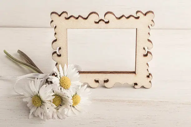 daisy flowers and a picture frame on wooden table / surface with copy space