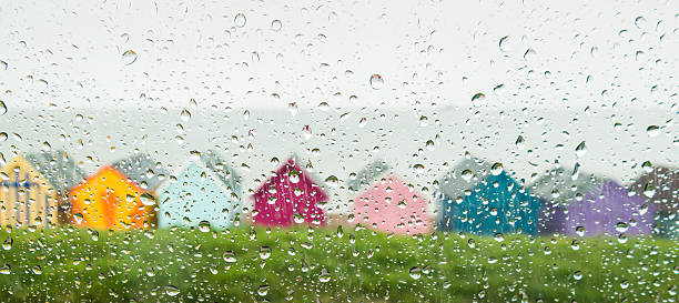 Rain drops on a car window looking at beach huts Rain drops on a car window on a wet day at the seaside in Herne Bay, Kent, Uk. Painted colourful beach huts can be seen in front of a grey sea. herne bay photos stock pictures, royalty-free photos & images