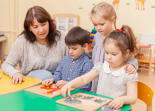 istock elementary school teacher collect puzzle with three pupils 518365498