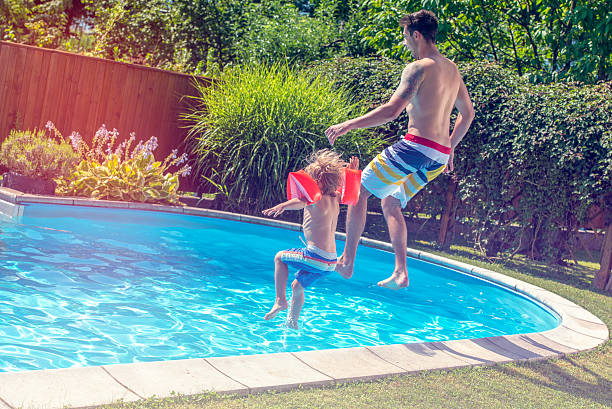 istock Father and son jumping into a pool 518365804