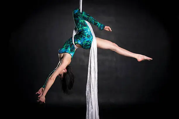 Aerialist woman doing some flexibility and strength tricks on silks