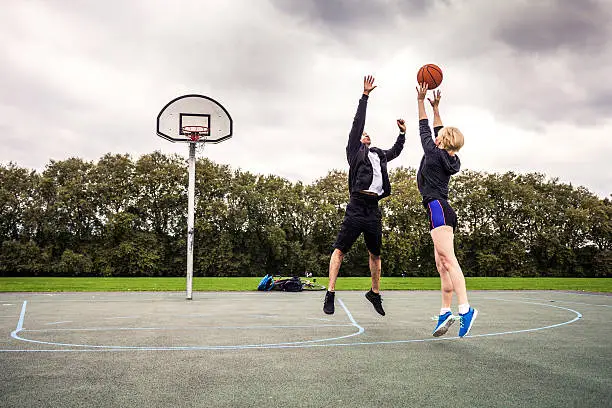 Basketball 1v1 man-woman in a London playground, UK.