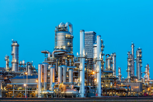 A large, modern petrochemical plant at dusk in industrial district near Rotterdam, Netherlands, Benelux, Europe. Distillation towers and other installations are visible against blue sky. 50 megapixel image taken with Canon EOS 5Ds, digital blending technique, long exposure with tripod.