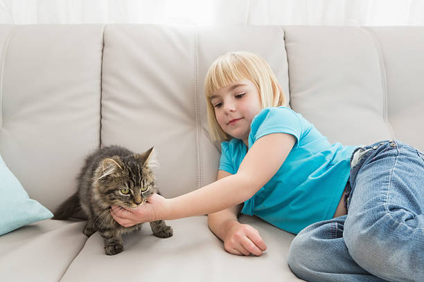 istock Little girl lying on the couch stroking her cat 518376675