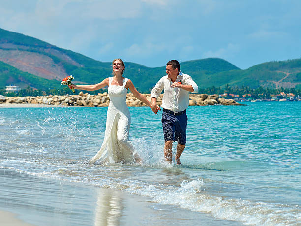 istock Happy Bride and groom running on beautiful tropical beach 518377829