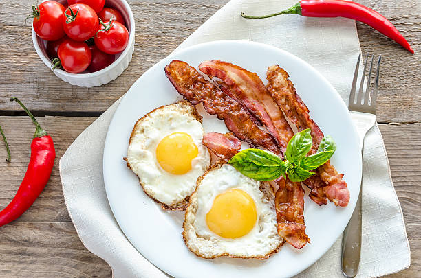 istock Fried eggs with bacon on the wooden table 518379131