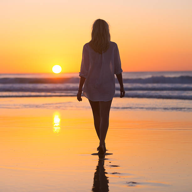 istock Lady walking on sandy beach in sunset. 518379720