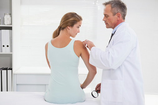 Doctor examining a patients shoulder in his office