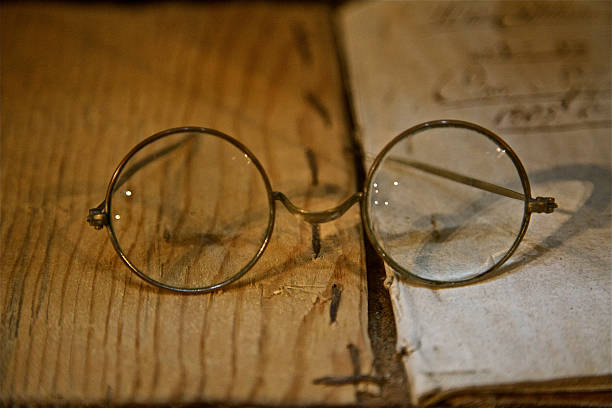 istock Old glasses round frame eyeglasses and old book 518382702
