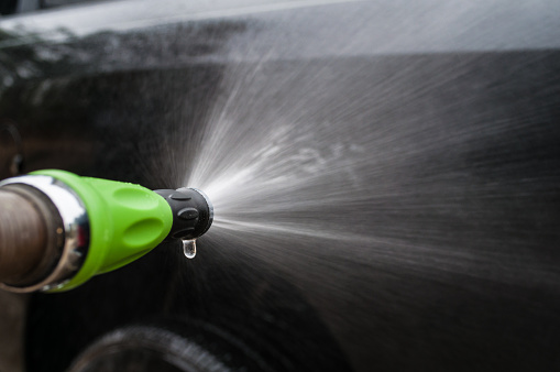 Green Water Nozzle Spraying water and Washing a Car.