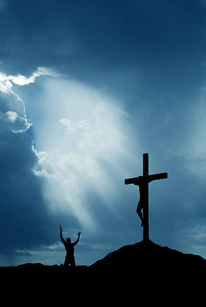 istock Dramatic sky scenery with cross and a worshiper vertical image 518394848