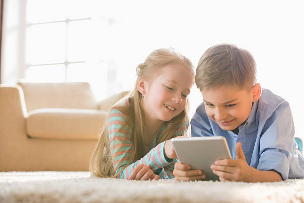 istock Brother and sister using digital tablet on floor at home 518399129