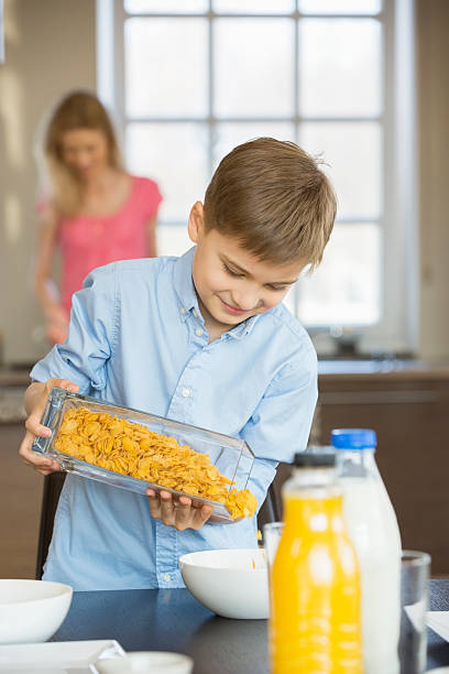Boy pouring corn flakes in bowl