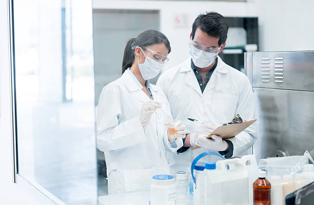 químicos trabalhando em um laboratório - chemical chemistry laboratory safety - fotografias e filmes do acervo