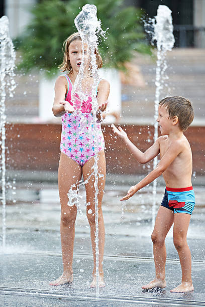 istock Happy children playing in a fountain 518400477