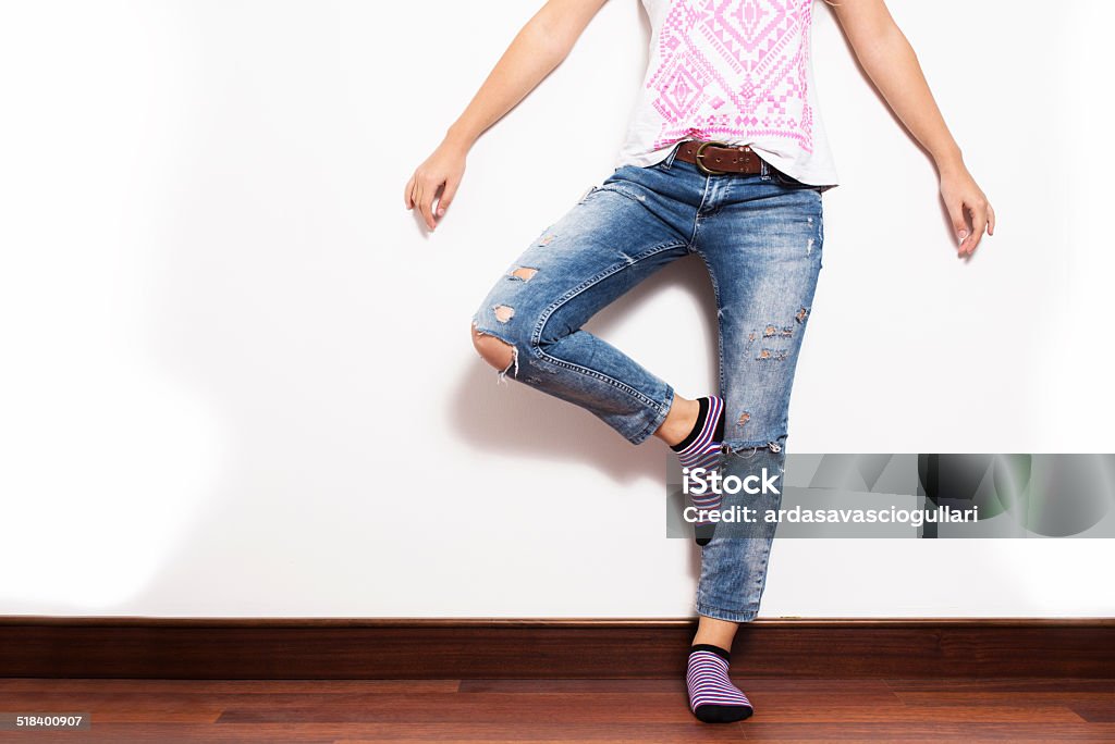 Tatty Jeans Woman in tatty jeans standing on one foot in frontof the white wall. Adult Stock Photo
