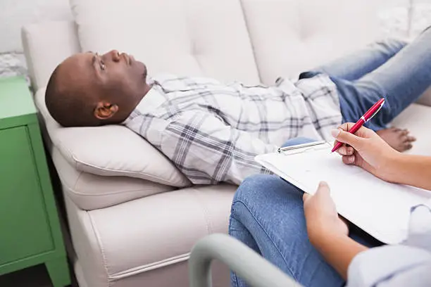 Photo of Man lying on sofa talking to his therapist