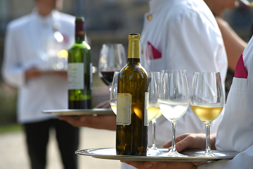 Waiters are serving vine at a wedding outdoor party
