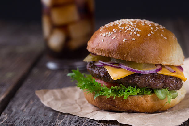 istock Juicy burger with cold cola on wooden background 518407960