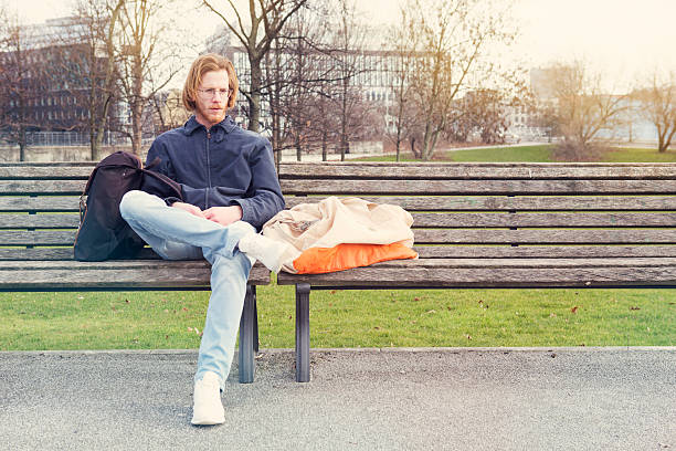 istock young man with his bags sitting on bench 518409416