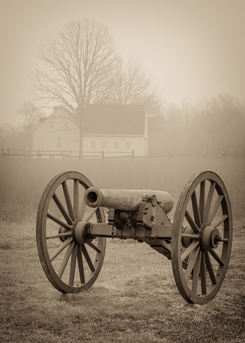 A civil war cannon with a farm house in the background at Cold Harbor