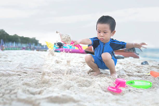 istock Boy splashing sand on the beach 518409470