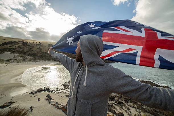 istock Cheerful young man on beach holding an Australian's flag 518409650