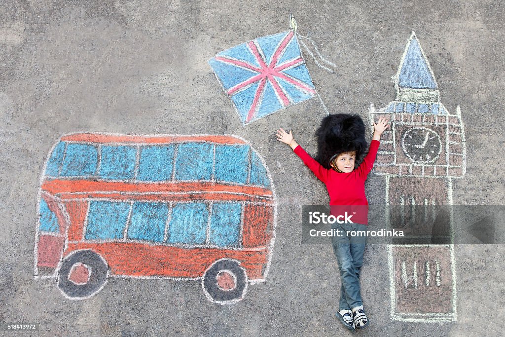 kid boy in british soldier uniform with London chalks picture Happy little kid boy in british queen's guard soldier uniform having fun with London picture drawing with colorful chalks. With Big Ben, Union Jack and red bus. London - England Stock Photo