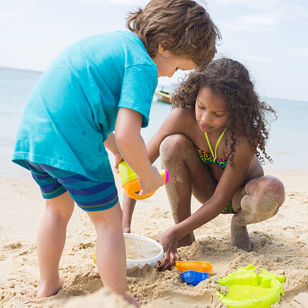 istock Children playing with sand during summer day on the beach. 518414504