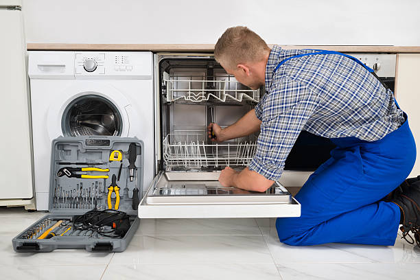 Man Repairing Dishwasher Young Man In Overall With Toolbox Repairing Dishwasher dishwasher stock pictures, royalty-free photos & images