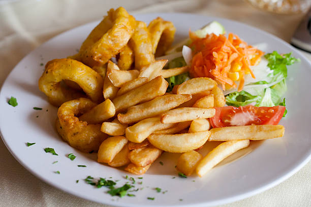 Fresh deepfried roman style squid served with fries and salad in local restaurant in Los Gigantes on tropical island Tenerife, Canary in Spain. Spanish food specialities.