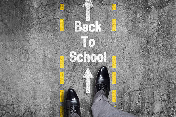 istock businessman standing back to school text written on blackboard 518426104