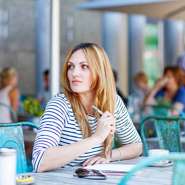istock Woman drinking coffee and writing notes in cafe 518428748