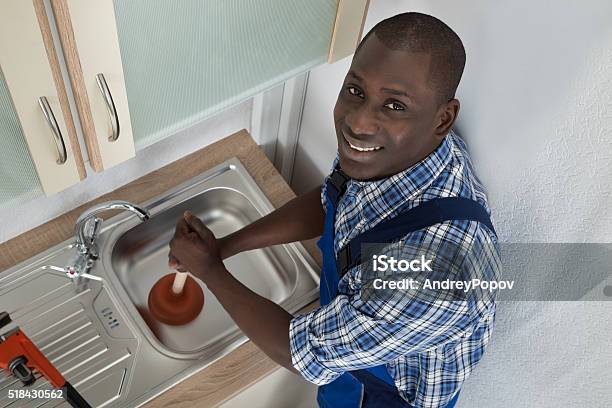 Plumber Using Plunger In Kitchen Sink Stock Photo - Download Image Now - African Ethnicity, African-American Ethnicity, Men