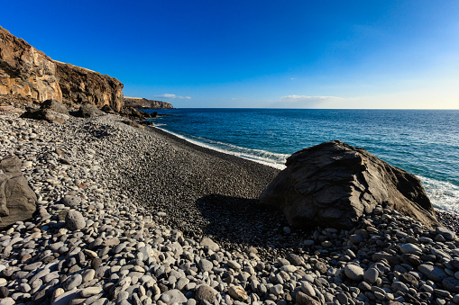 Summer seascape on tropical island Tenerife, Canary in Spain. Playa de San Juan beach full of rocks.