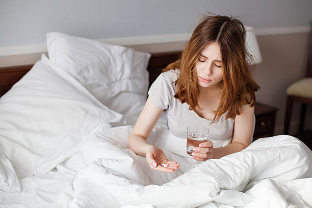 istock Sick woman looking on pills in her hand 518458388