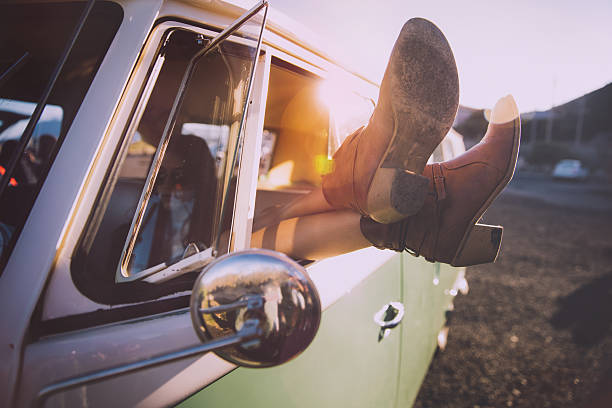 Young woman relaxing during a road trip with vintage van Young woman relaxing by crossing legs out of the window of a nice vintage van on sunset boot photos stock pictures, royalty-free photos & images