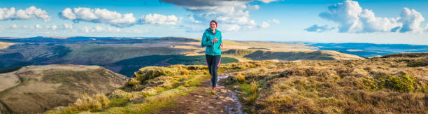 istock Young woman trail running along wilderness path mountain ridge panorama 518462368