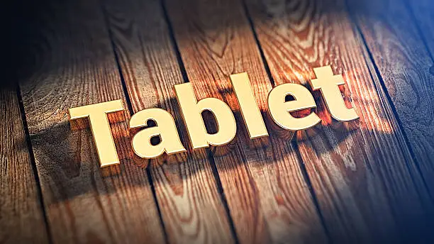 The word "Tablet" is lined with gold letters on wooden planks. 3D illustration pic