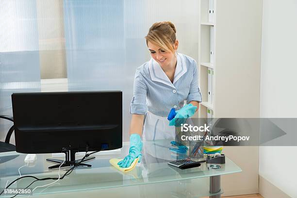 Maid Cleaning Desk With Feather Duster Stock Photo - Download Image Now - Adult, Blue-collar Worker, Care