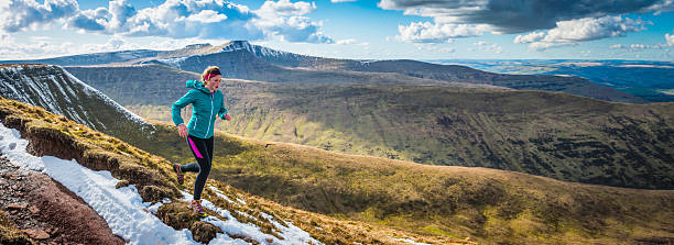 istock Young woman running on wilderness trails on mountain ridge panorama 518462878