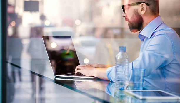 Hipster manager in cafe, working on laptop by window
