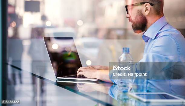 Hipster Manager In Cafe Working On Laptop By Window Stock Photo - Download Image Now