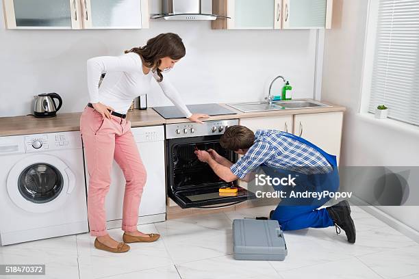 Woman Looking At Worker Repairing Oven Stock Photo - Download Image Now - Adult, Adults Only, Appliance